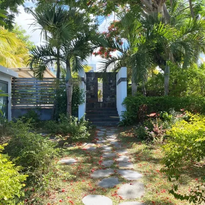 Villa entrance surrounded by luscious green shrubbery and palm trees.