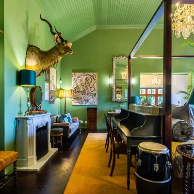 Bright green bedroom with four poster bed, fireplace and hunting trophy. House Nouveau.