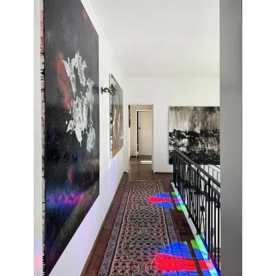 Second level of Villa Toscana with parquet flooring covered with a narrow Persian rug and white washed walls with large abstract paintings.