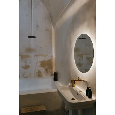 Casa Piano bathroom with ceramic washbasin and round light up mirror mounted on a whitewashed wall.