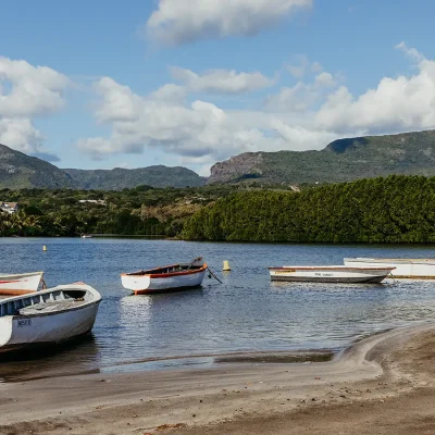 Black River estuary shore line scattered with fisherman's boats and the Black River National Park mountain range in the distance.