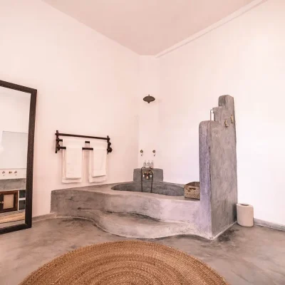 The Fort bathroom suite with whitewashed walls and screed floors that is elevated with the built in bath tub, and a large mirror.