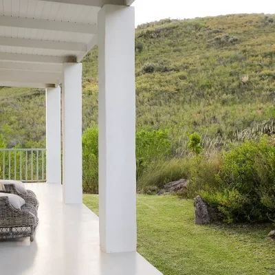 Buchubos villa verandah with large wicker armchairs facing the green landscape.