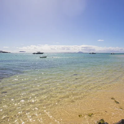 Crystal turquoise ocean water meeting coastal beach and rocks.