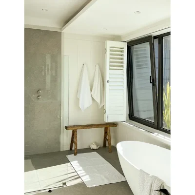 Bathroom with glass enclosed shower and bathtub, beige tiling and large windows. Oasis on Glen.