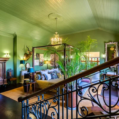 Bright green bedroom with four poster bed, chandelier and wrought iron staircase. House Nouveau.