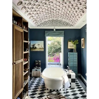 Bathroom with navy blue walls, an arched ceiling with seashells and a central white bath tub facing a door opening onto the patio.