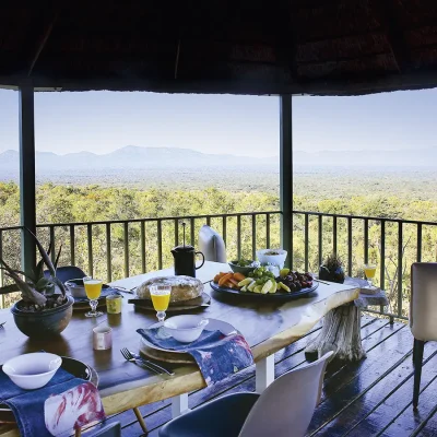 Outdoor dining table set on an elevated deck overlooking the vast terrain and mountainous landscape. Manor House.