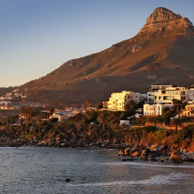 Sunset over Camps Bay, highlighting the magnificent Lion's Head mountain slopes, and lighting up the faces of costal properties.