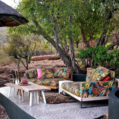 Secluded outdoor lounging with tropical print sofas and wooden coffee table nestled under the trees.