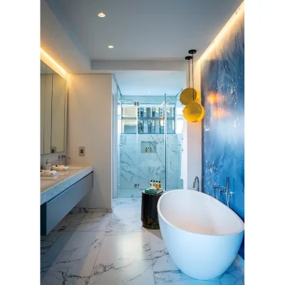 En suite bathroom with galaxy print wallpaper, a large freestanding bath, a large glass enclosed shower with marble tiling and a marble twin washbasin. Labotessa Hotel.