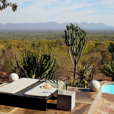 Sunbathing area with elevated sunbeds overlooking the swimming pool and Waterberg bush and distant mountains.