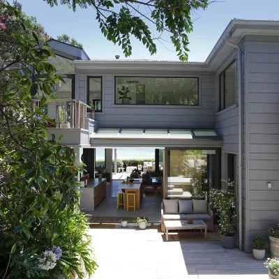 Modern open plan beach house with grey cladded walls, large windows and glass stack back doors that reveals a flood of natural light and views of the ocean.