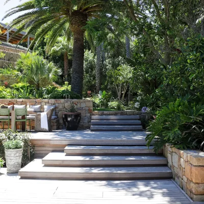 Back garden of Oasis on Glen with a wooden stair case leading to a secluded outdoor dining table and chairs under the trees.