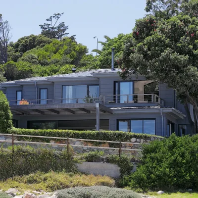 Face of Oasis On Glen with grey cladded walls and large windows, and surrounded by luscious trees.